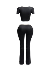 Back view of black two-piece set with nude trim, showing fitted crop top and curve-hugging flared pants.